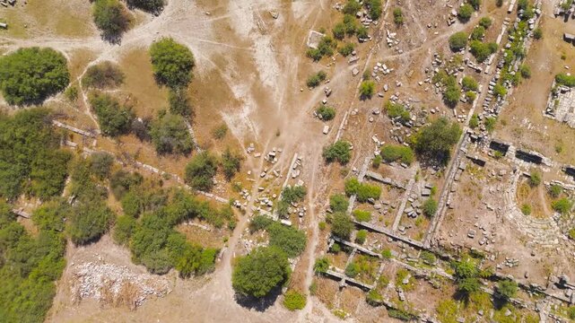 Balat, Turkey. Aerial drone flight over the ancient political heart of Miletus, revealing the Bouleuterion council house, North Agora colonnades, and Delphinion sanctuary ruins under bright summer su