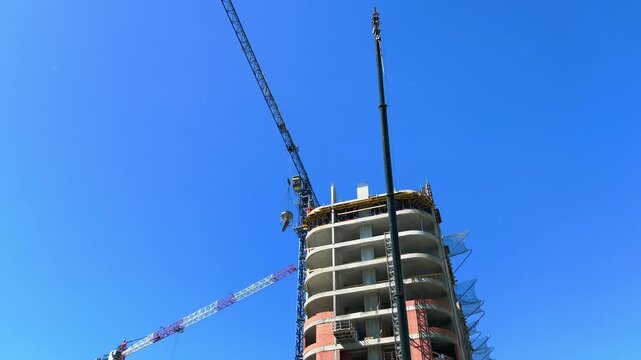 Unfinished apartment tower with construction crane lifting equipment