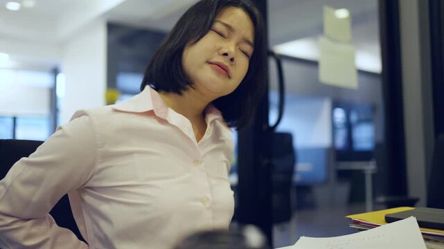 Young Asian woman working at office and have a pain office syndrome