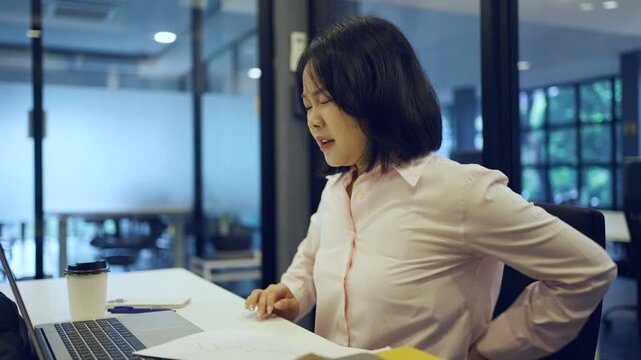 Young Asian woman working at office and have a pain office syndrome