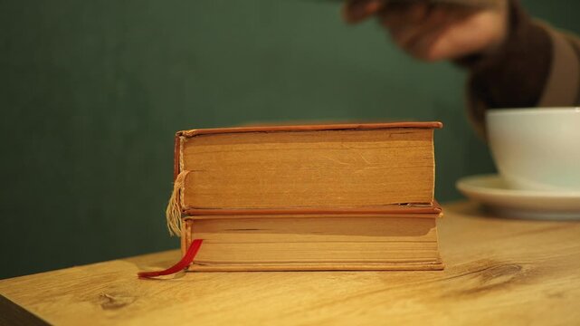 Books stacked on a table with a cup in the background