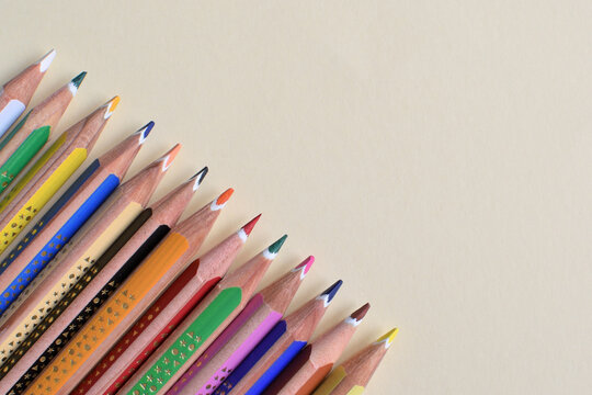 Colored pencils arranged diagonally on a pastel yellow background.