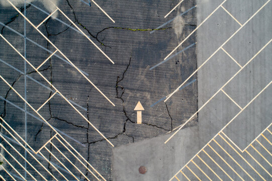 Drone view reveals cracked concrete and directional yellow arrow