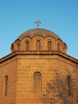 A vertical close-up shot capturing the detailed stone dome and cross of the Church of the Nativity of the Blessed Virgin Mary against a clear blue sky in Vanadzor, Armenia.