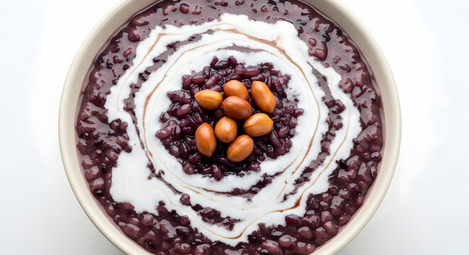 Bubur pulut hitam from Malaysia served with coconut milk and peanuts on top taken in high angle macro shot against white background