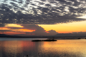 Fototapeta premium Sunset Over Calm Water with Dramatic Clouds
