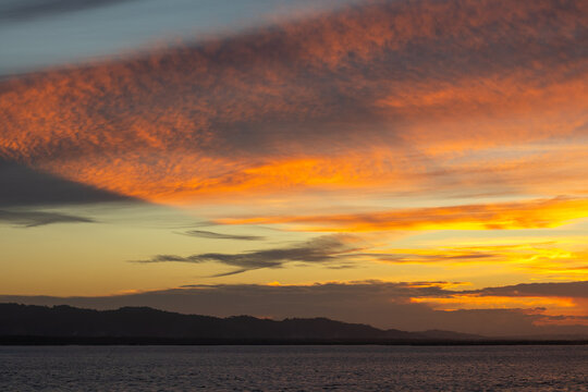 Vibrant Sunset Over Water and Hills