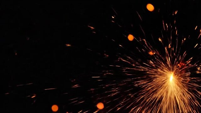 Bright golden sparks explode against a deep dark black background