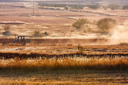 Farm tractor plowing agricultural land in La Mancha at golden hour