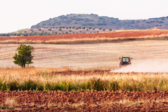 Tractor Plowing Red Soil Fields in Alhambra Landscape