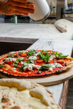 Artisan pizza with burrata and olives on a pizzeria table
