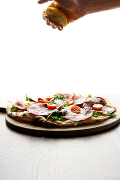 A pizzaiolo squeezes lemon juice onto a freshly baked pizza