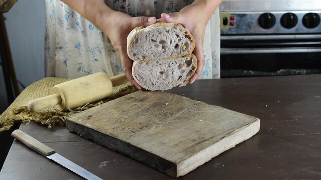Baker checking the softness of a sliced artisan sourdough bread loaf by pressing it, showing the open crumb structure and crispy crust. Represents traditional baking, healthy food, and handmade crafts