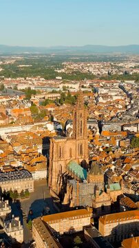Vertical video. Strasbourg, France. Strasbourg Cathedral, a single Gothic spire rising 142 meters above terracotta rooftops, Drone footage on a clear summer morning. Drone footage, Point of interest