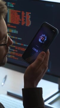 Over-the-shoulder view, of man holding smartphone, talking with AI chatbot app, asking questions, using artificial intelligence assistant for work and daily tasks on phone and computer. Vertical video