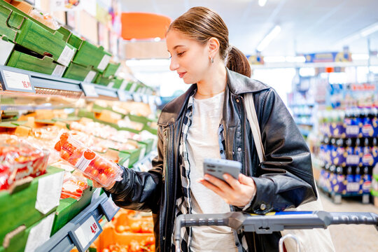 Girl Shopping In Supermarket Chooses Tomatoes