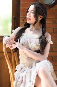 Elegant young woman relaxing indoors with natural light on her face and fashionable dress