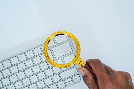 Magnifying glass held over delete key on white computer keyboard