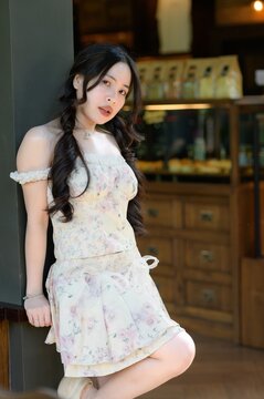 Elegant young woman with long black hair wearing a floral dress in cozy cafe setting