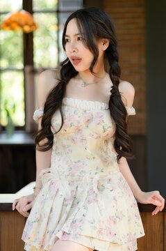 Young woman with long dark hair wearing floral dress in cozy indoor setting