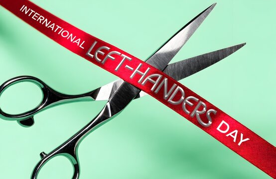 International left-handers day conceptual red ribbon cutting with scissors