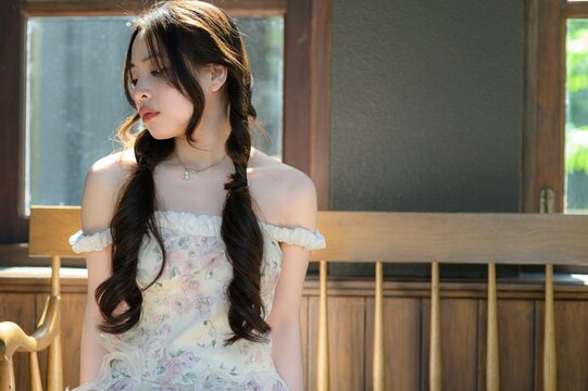 Young woman with braided hair sitting by window during sunny daytime in cozy indoor setting