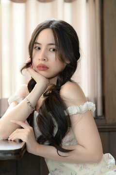 Elegant young woman with long dark hair and soft expression in cozy interior setting