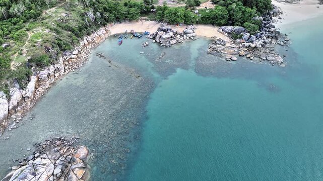 Aerial Drone View of Turun Aban Beach Bangka Featuring Crystal Clear Turquoise Waters Granite Rock Coastline Tropical Forest and Quiet Fishing Boats