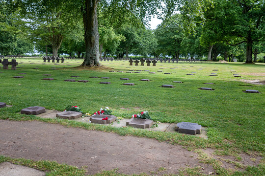 La Cambe, France - June 4, 2026: La Cambe German War Cemetery in Normandy France with rows of dark stone grave markers on green grass under large trees historic World War II military graveyard.