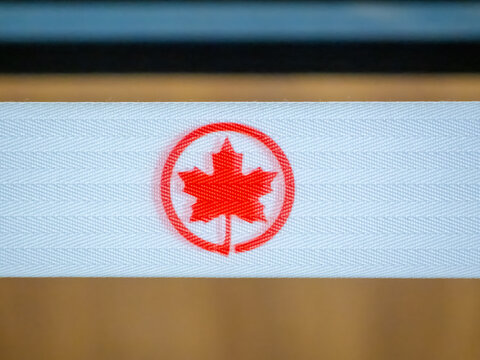 Ottawa, Ontario, Canada. July 18, 2026. Macro close-up of a red Air Canada maple leaf logo printed on a white woven strap.