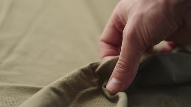 Slow motion man hand checking green cotton jersey cloth