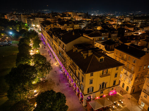 Drone shot of the historic Liston buildings and narrow streets of Corfu Old Town illuminated with traditional purple lighting during Holy Week festivities at night
