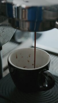 4K Pouring coffee stream from professional machine in cup. Barista man making double espresso, using filter holder. Flowing fresh ground coffee. Drinking roasted black coffee in the morning.	
