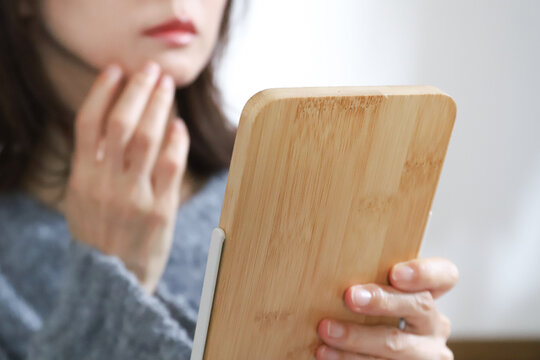鏡で肌の状態をチェックする女性