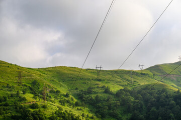 Obraz premium Landscape featuring electrical transmission lines over verdant hillsides under o