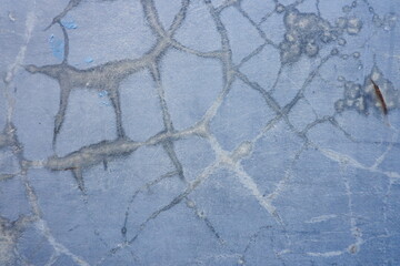 Detailed texture of aged blue paint with irregular crack lines, forming a vintage distressed wall background with natural patterns. © Sije