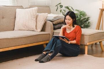 Young woman sitting on the floor using a digital tablet at home © PRIME STOCK LAB