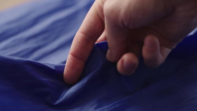 Slow motion man hand checking blue synthetic bag fabric
