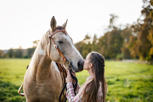 Woman kissing her horse, showing trust, emotional connection and friendship between people and animal