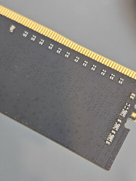 Macro photograph of a black printed circuit board showing electronic components, surface texture and gold connector contacts for computer hardware, technology and electronics concepts.