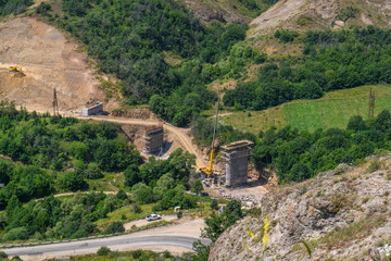 Obraz premium Construction site with crane and stone ruins in lush green valley