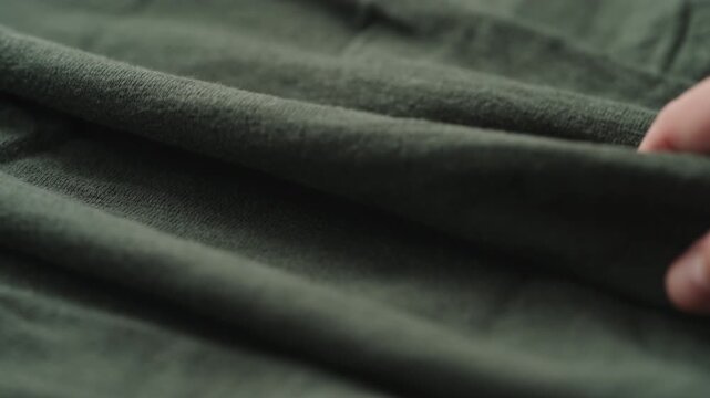 Slow motion man hand checking green linen jersey cloth