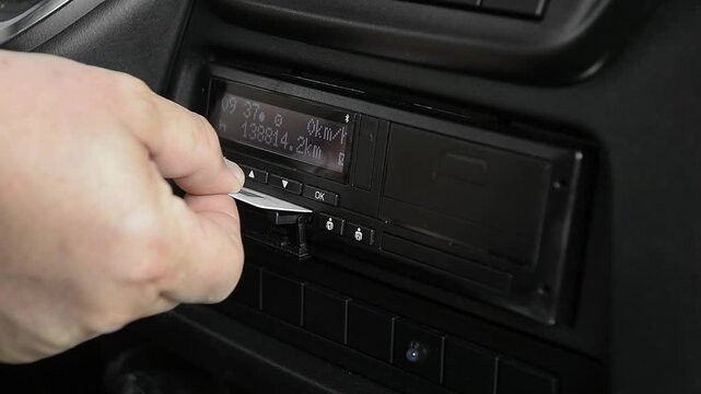 Driver removing smart chip card from tachograph slot