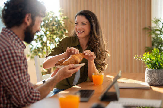 Couple sharing breakfast croissants and orange juice at home