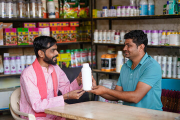 Fototapeta premium Indian fertilizer shop keeper giving pesticide bottle to farmer