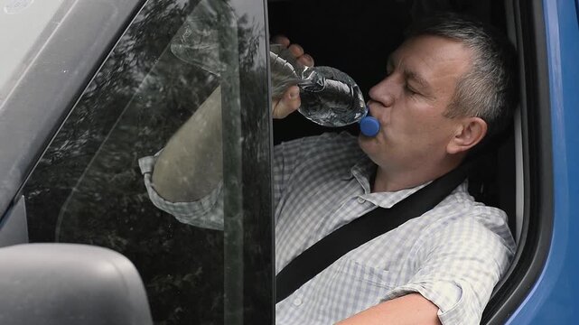 Thirsty truck driver eagerly drinking water from bottle