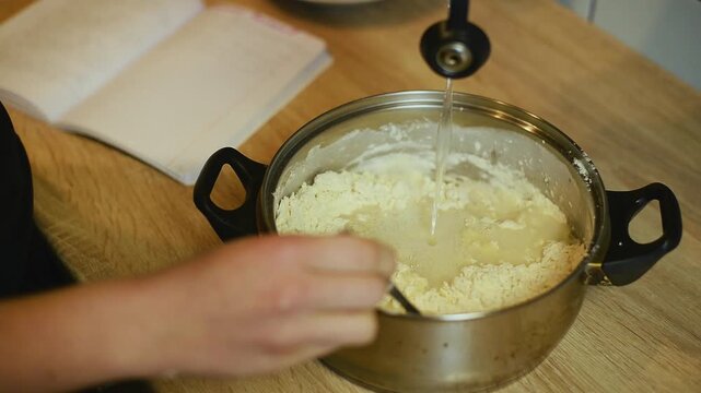 Pouring water into flour mixture for making dough