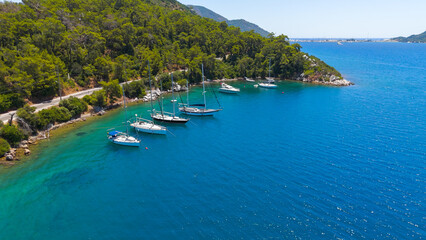 Marmaris, Turkey. Yachts anchored along wild forested coastline with road in Marmaris Bay. Aerial view showing untouched nature and turquoise water on sunny day.. Aerial View © Video Render