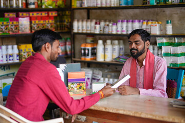 Fototapeta premium indian farmer and fertilizer shop owner discussing while looking some product