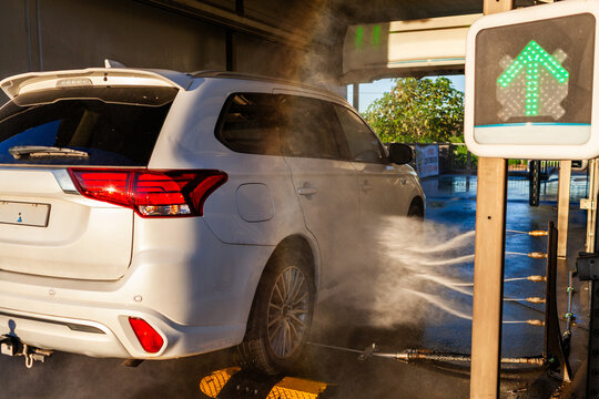 vehicle driving into automatic car wash bay with underbody spray washing cycle